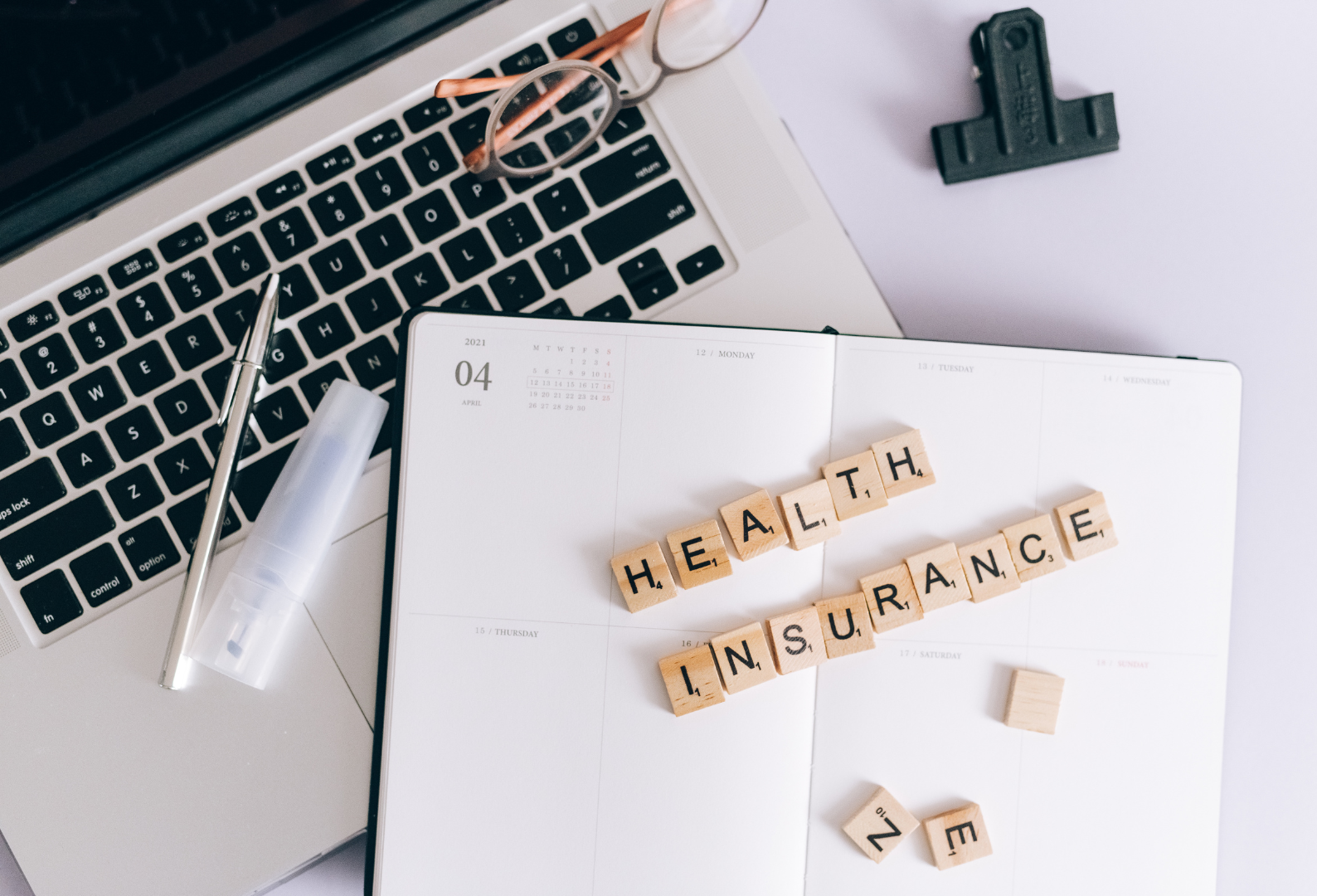 a notebook with the word health insurance written on it next to a laptop .