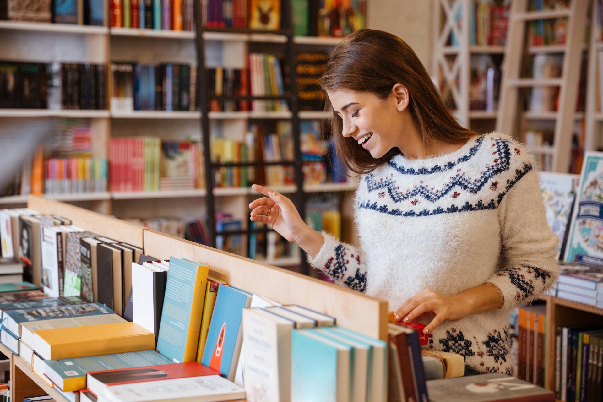 Portrait of a beautiful brunette woman looking for a book in store