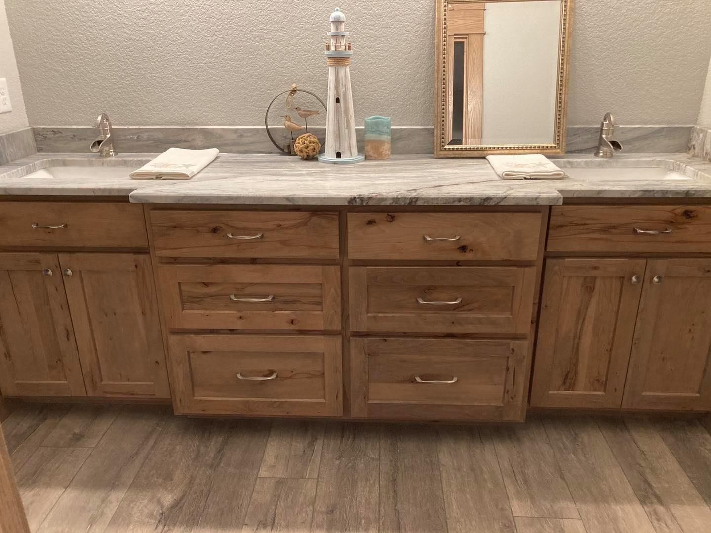 A bathroom with two sinks , a mirror and wooden cabinets.