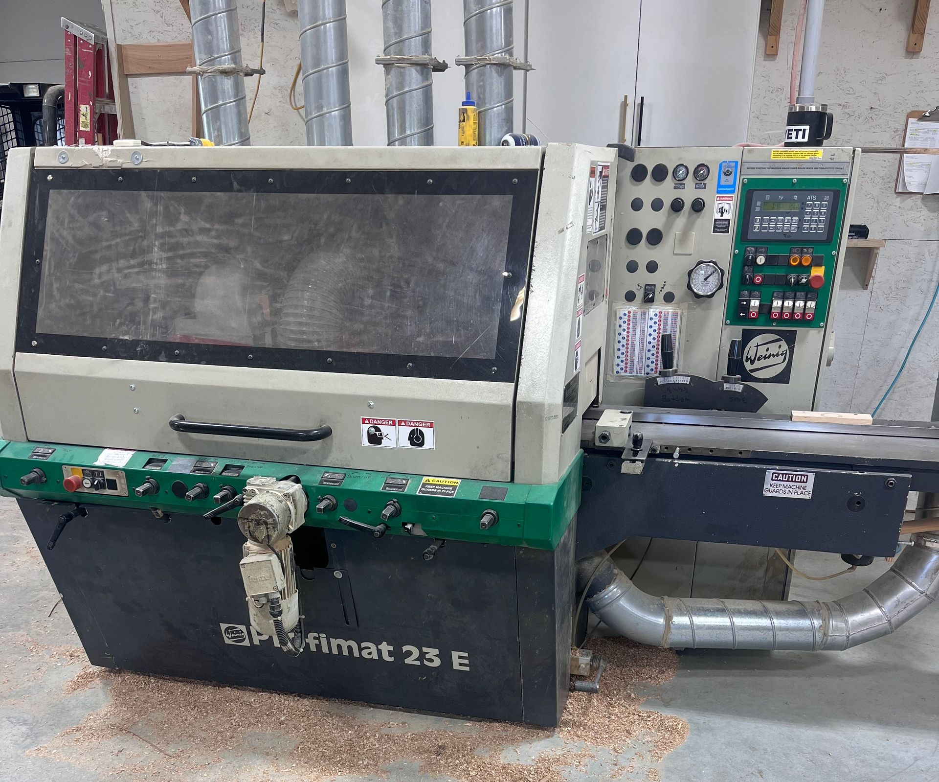 A woodworking machine, white and green, with controls and a dust collection system.