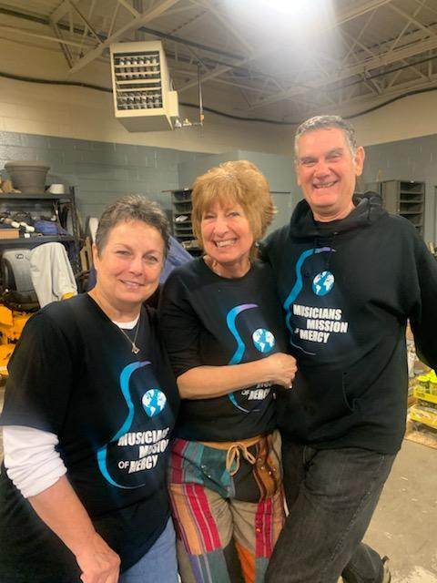 A man and two women are posing for a picture in a garage.