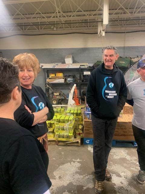 A group of people are standing in a warehouse talking to each other.