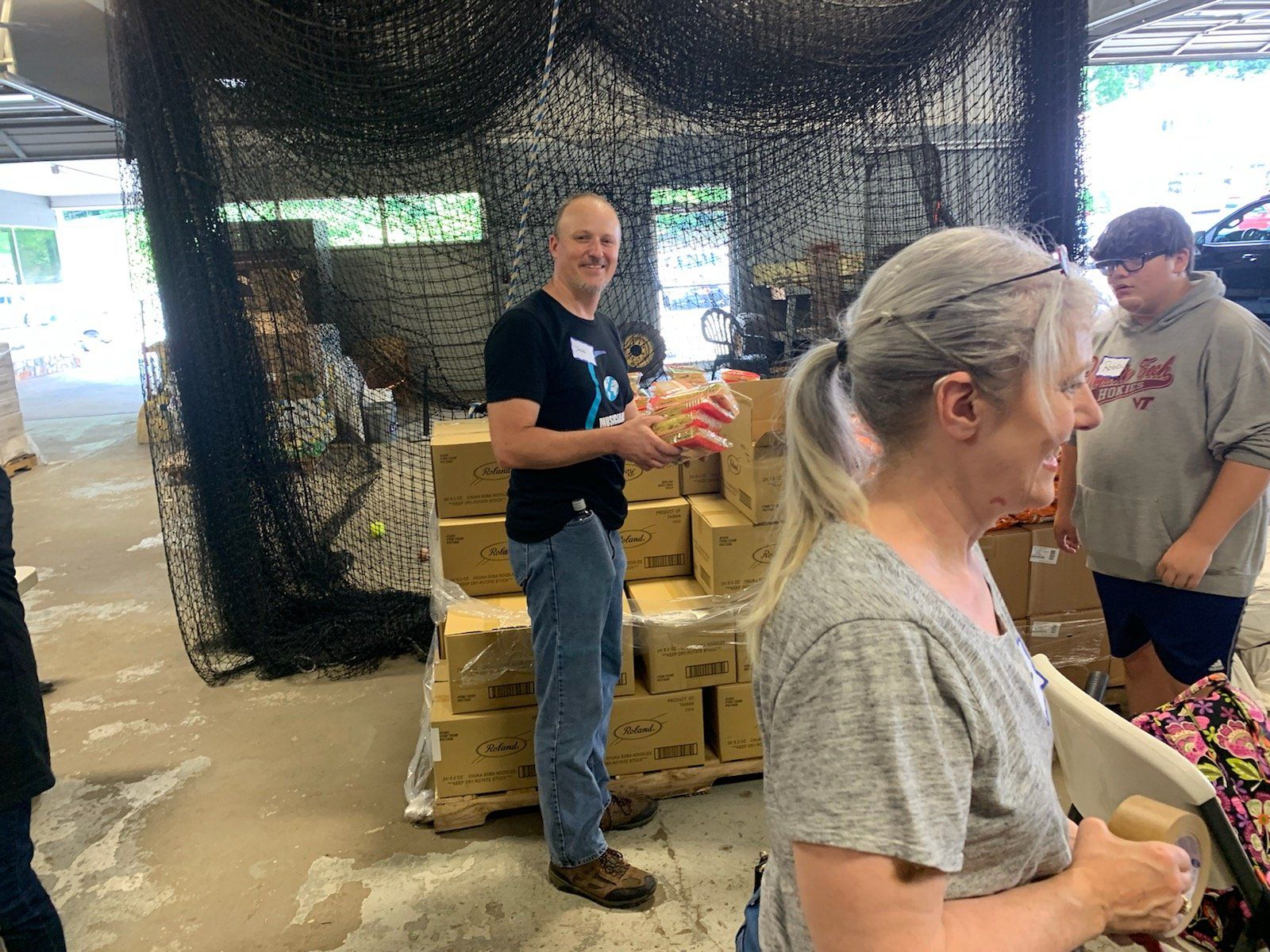 A man and a woman are standing in front of a pile of boxes.