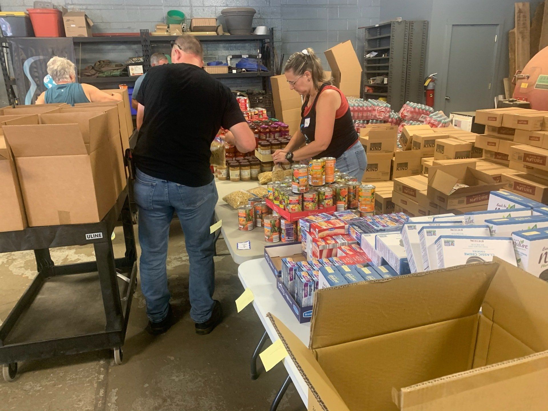 A group of people are standing around a table in a warehouse.