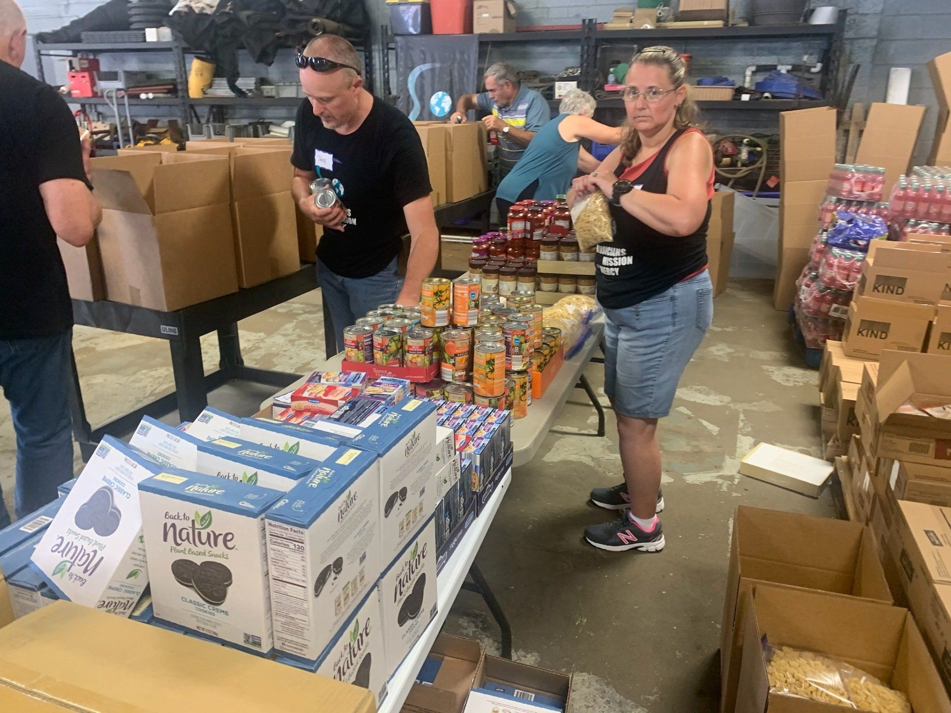 A group of people are standing around a table in a warehouse.