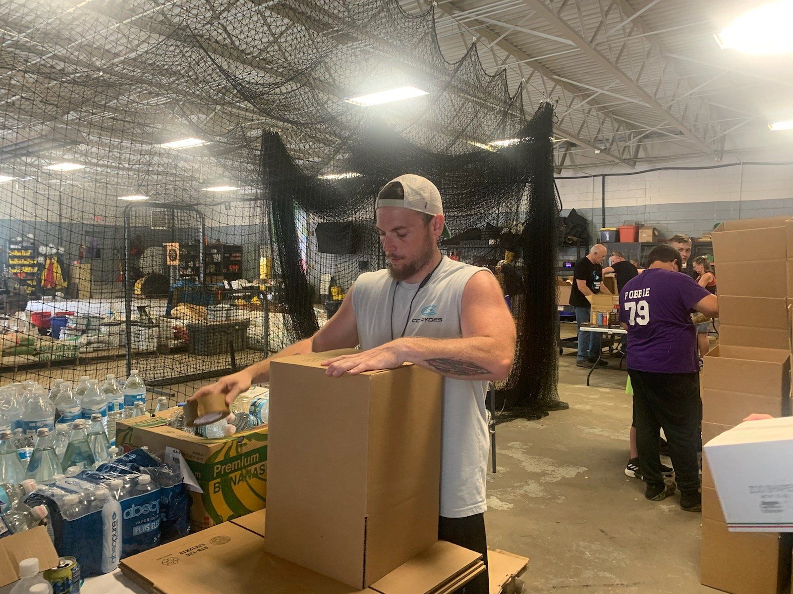 A man is packing a cardboard box in a warehouse.