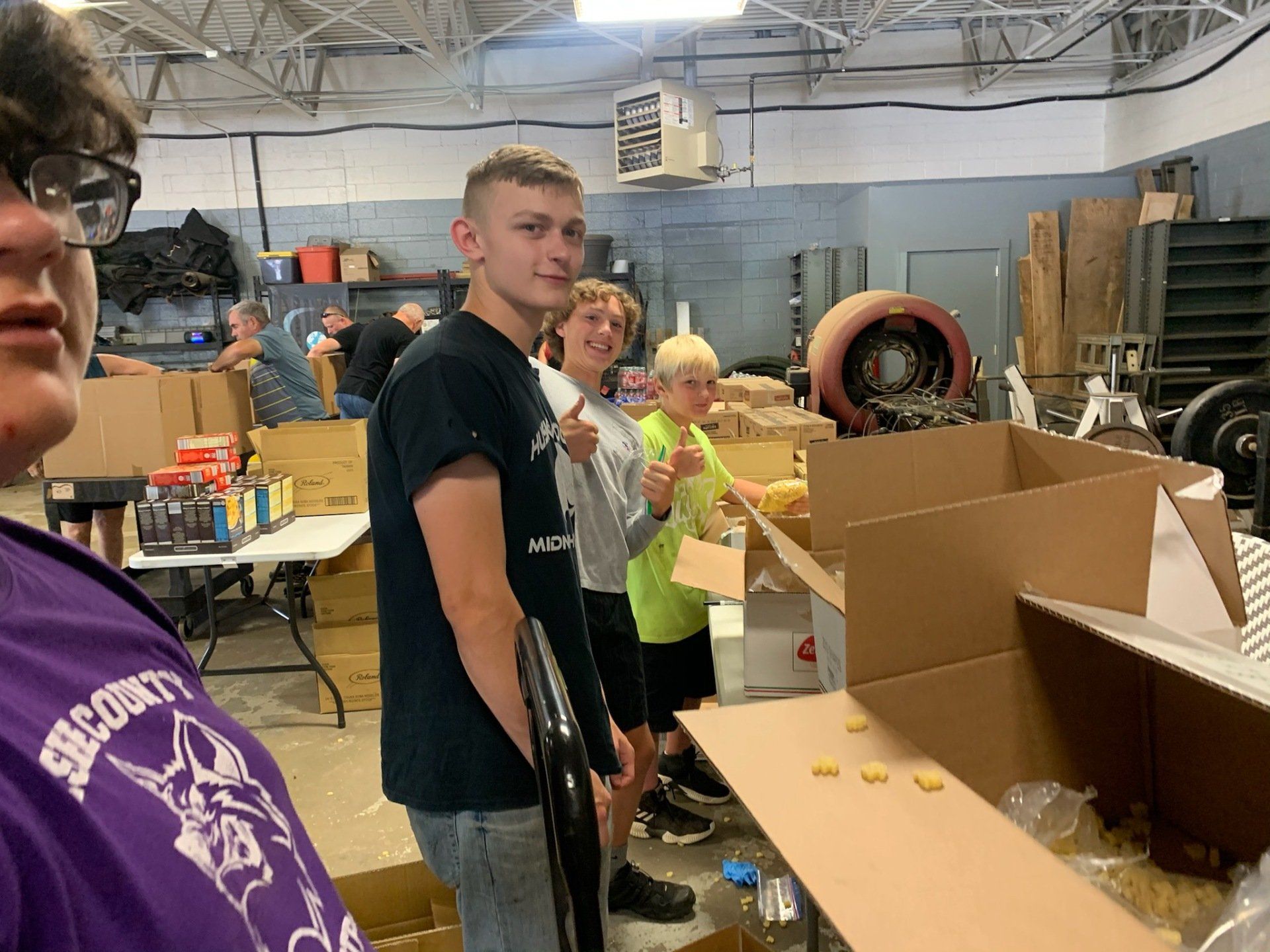 A group of people are standing in a room filled with boxes.