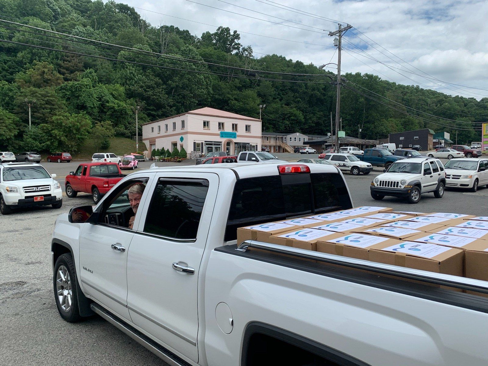 A white truck with boxes in the back is parked in a parking lot.