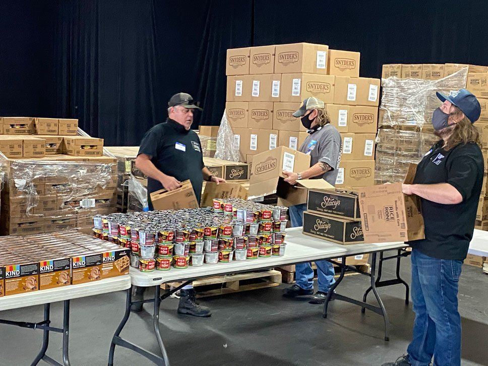 A group of people are standing around a table in a warehouse.