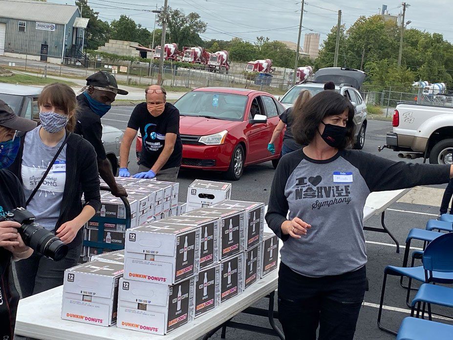 A group of people are standing around a table with boxes on it.