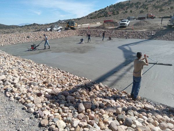 People laying rocks on a concrete slope at a dry hillside construction site