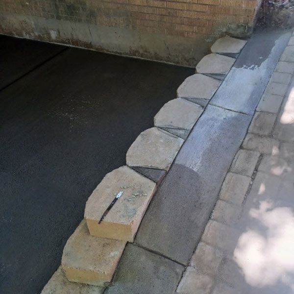 Stone blocks lining the edge of a canal beside a paved walkway, with a small object on top