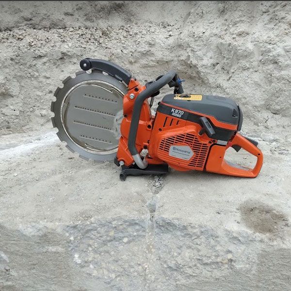 Orange concrete saw resting on a rough stone surface