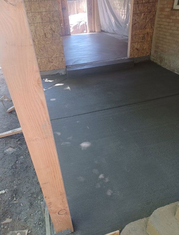 Partially finished room with dark concrete floor, wooden post, and doorway at the back
