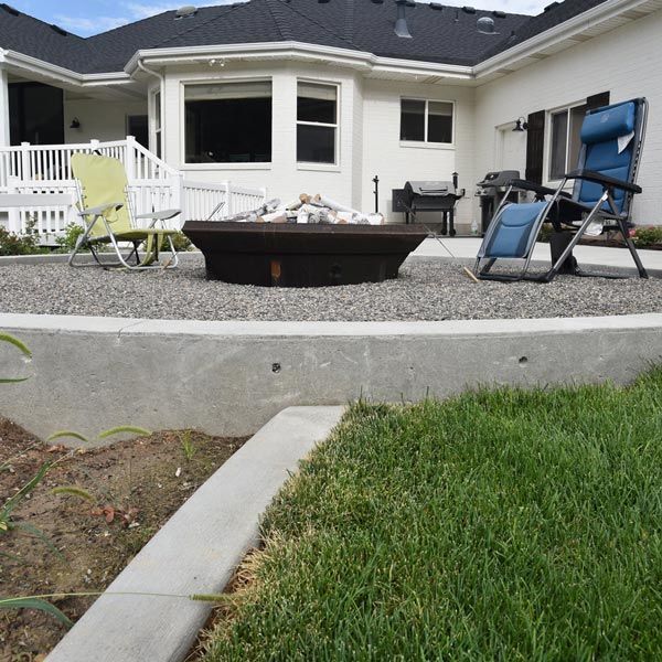Backyard patio with a fire pit, lounge chairs, and a white house deck behind it