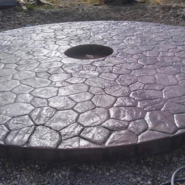 Round stone-textured table top with a central hole, outdoors on grass.