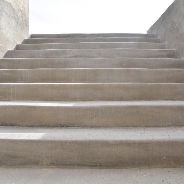 Concrete staircase leading upward between white walls