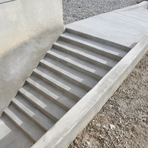 Concrete outdoor stairway beside a wall, descending into a gravel area