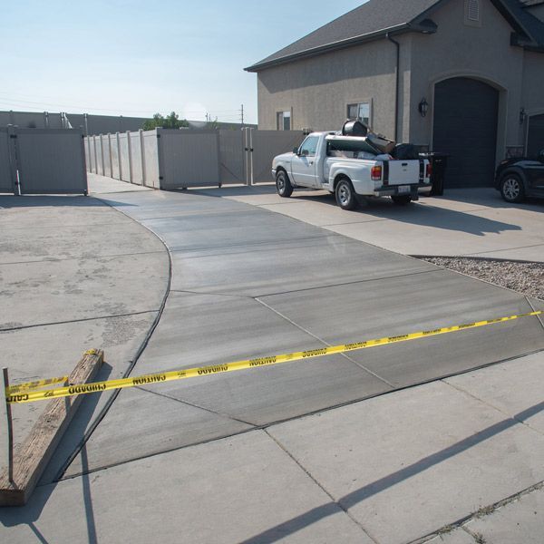 Driveway leading to a garage, with a pickup truck and caution tape across the foreground.