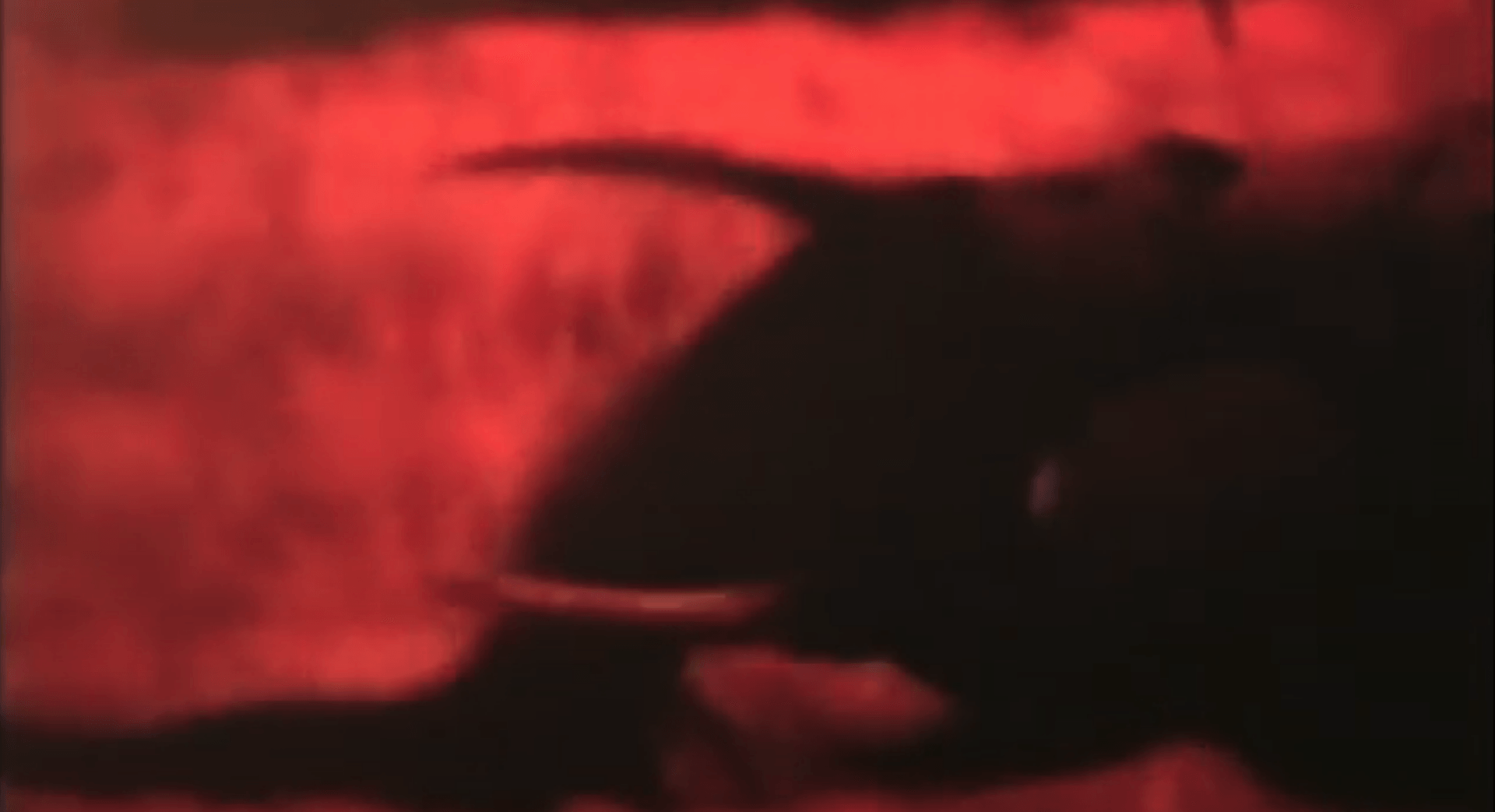Dark silhouette of a person against a vivid red background