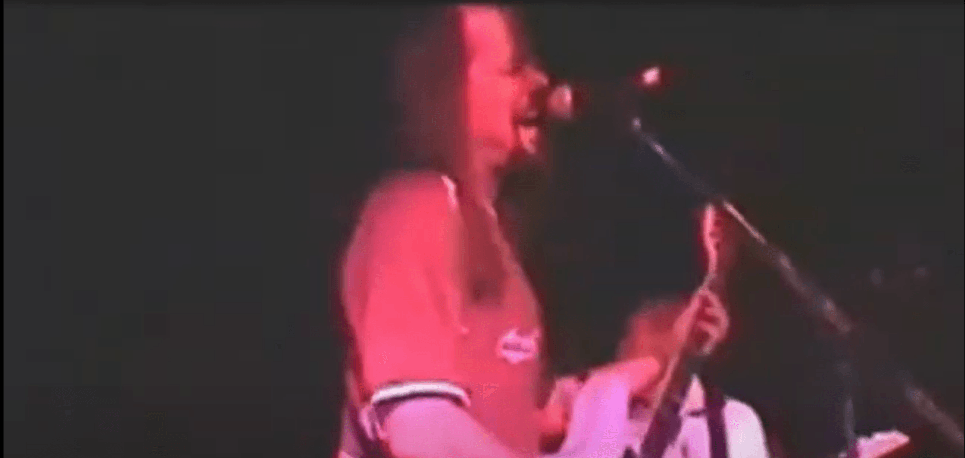 Singer performing into a microphone under red stage lighting