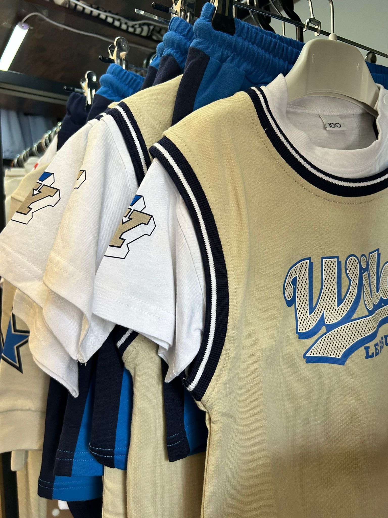 Magliette blu e bianche appese a uno stendino, con una maglia color crema in primo piano.