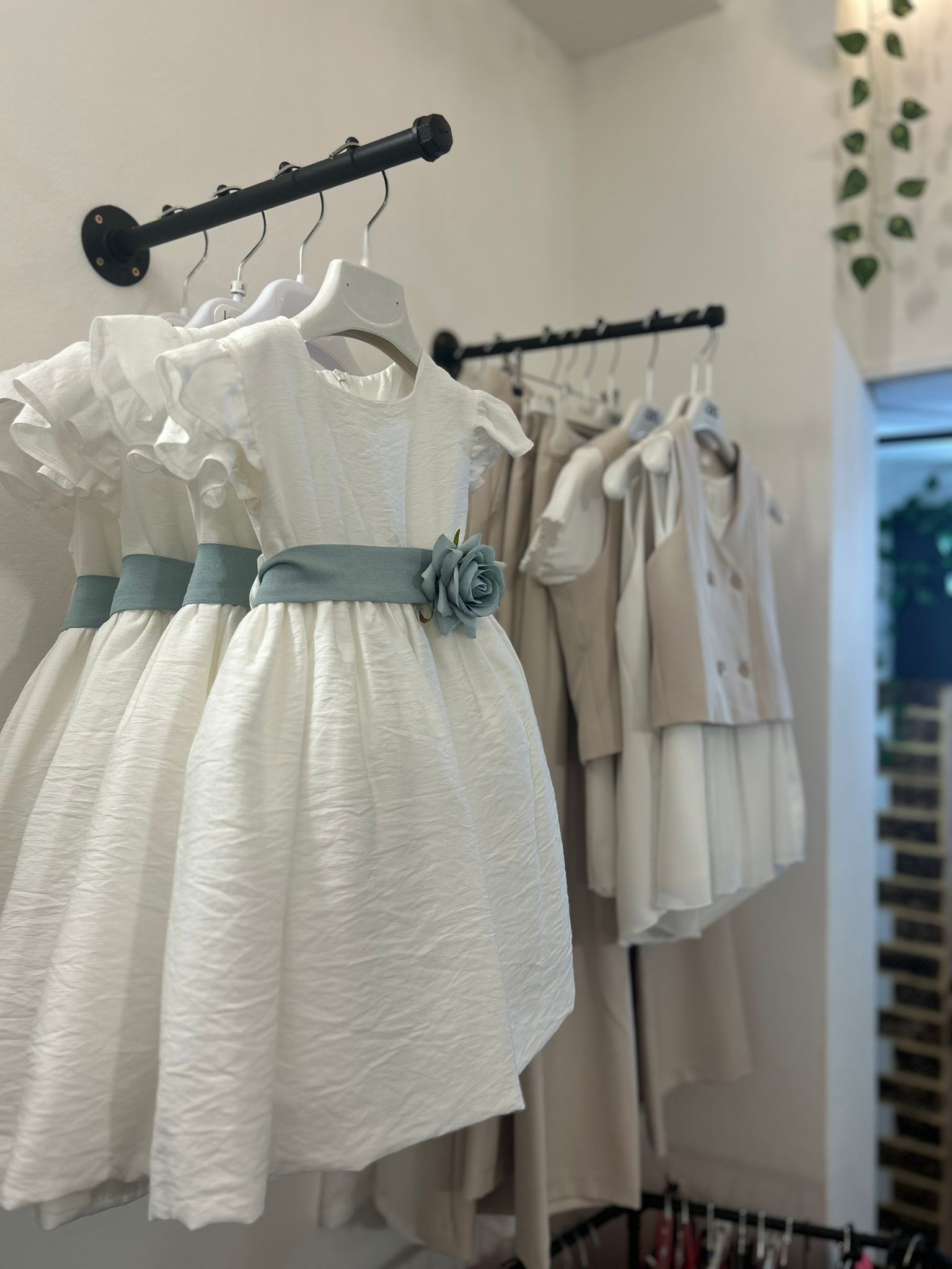 Abiti bianchi su appendiabiti neri in una luminosa boutique.
