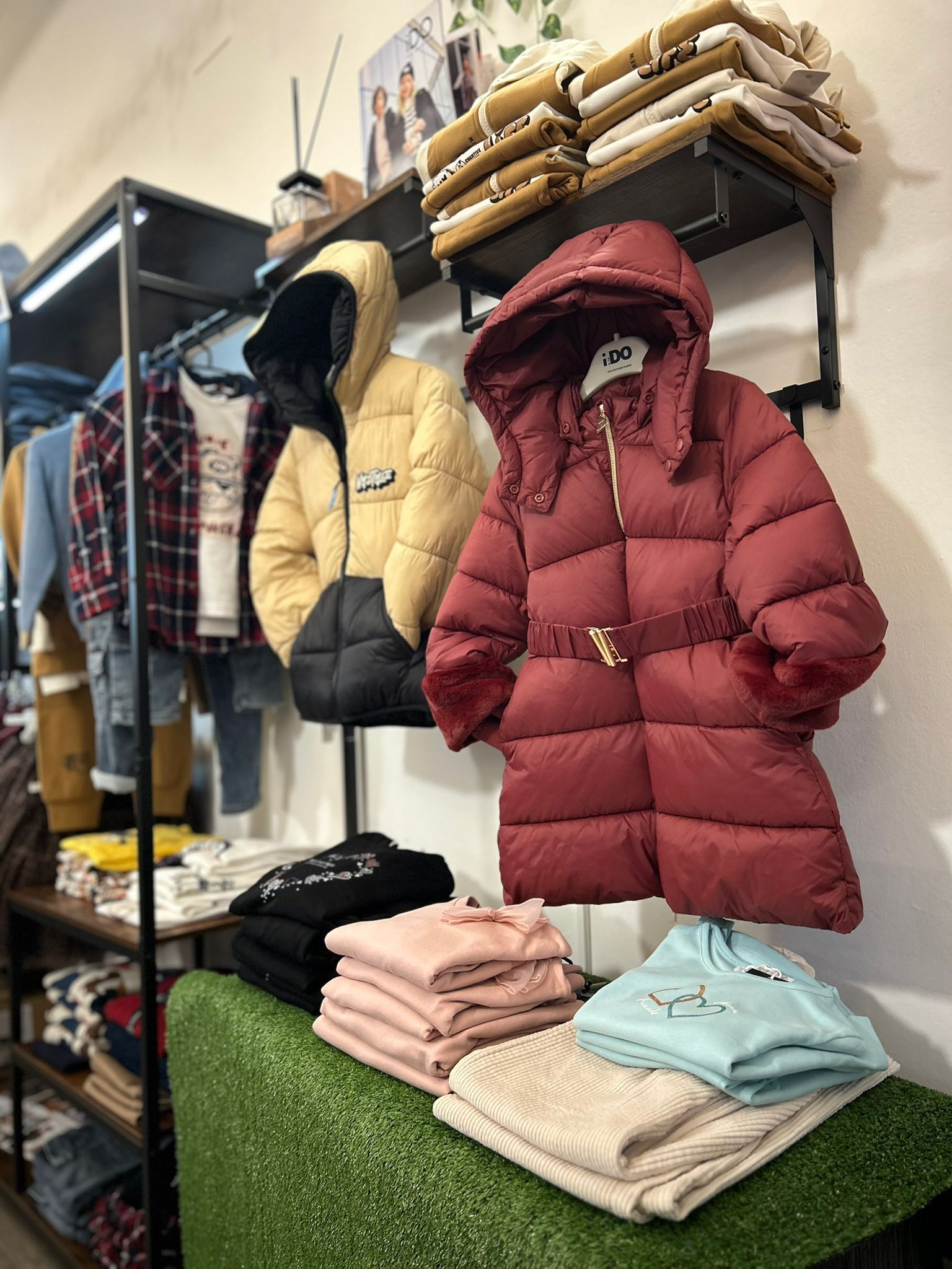 Cappotti e maglioni piegati esposti sugli scaffali di un negozio di abbigliamento.
