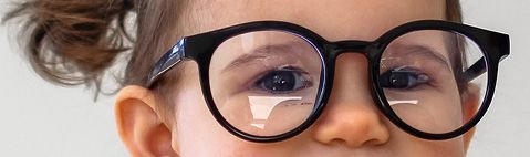 Primer plano de una persona que lleva gafas redondas con montura negra, mirando a la cámara.