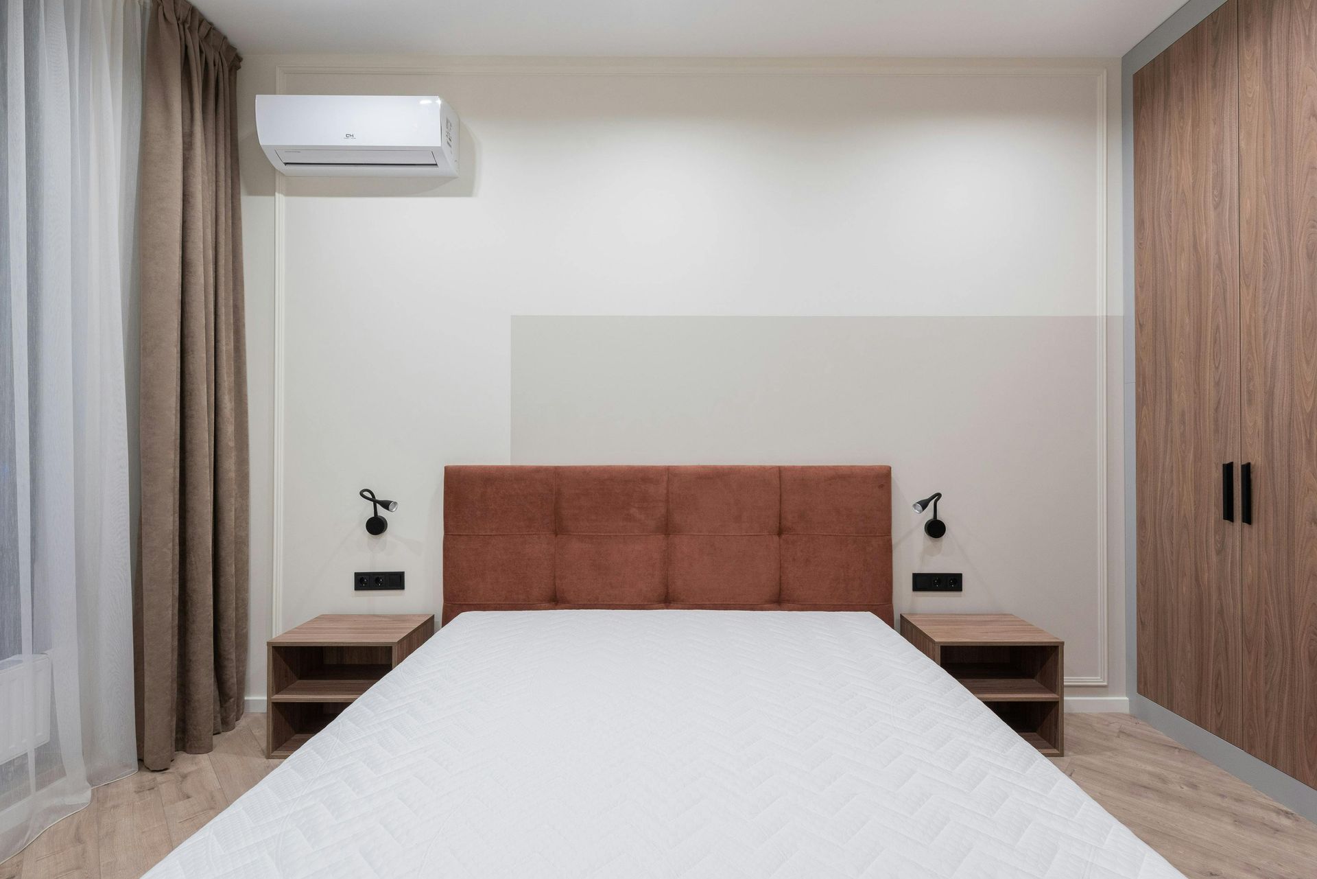 Bedroom with brown headboard, nightstands, and wardrobe; air conditioner mounted on wall.