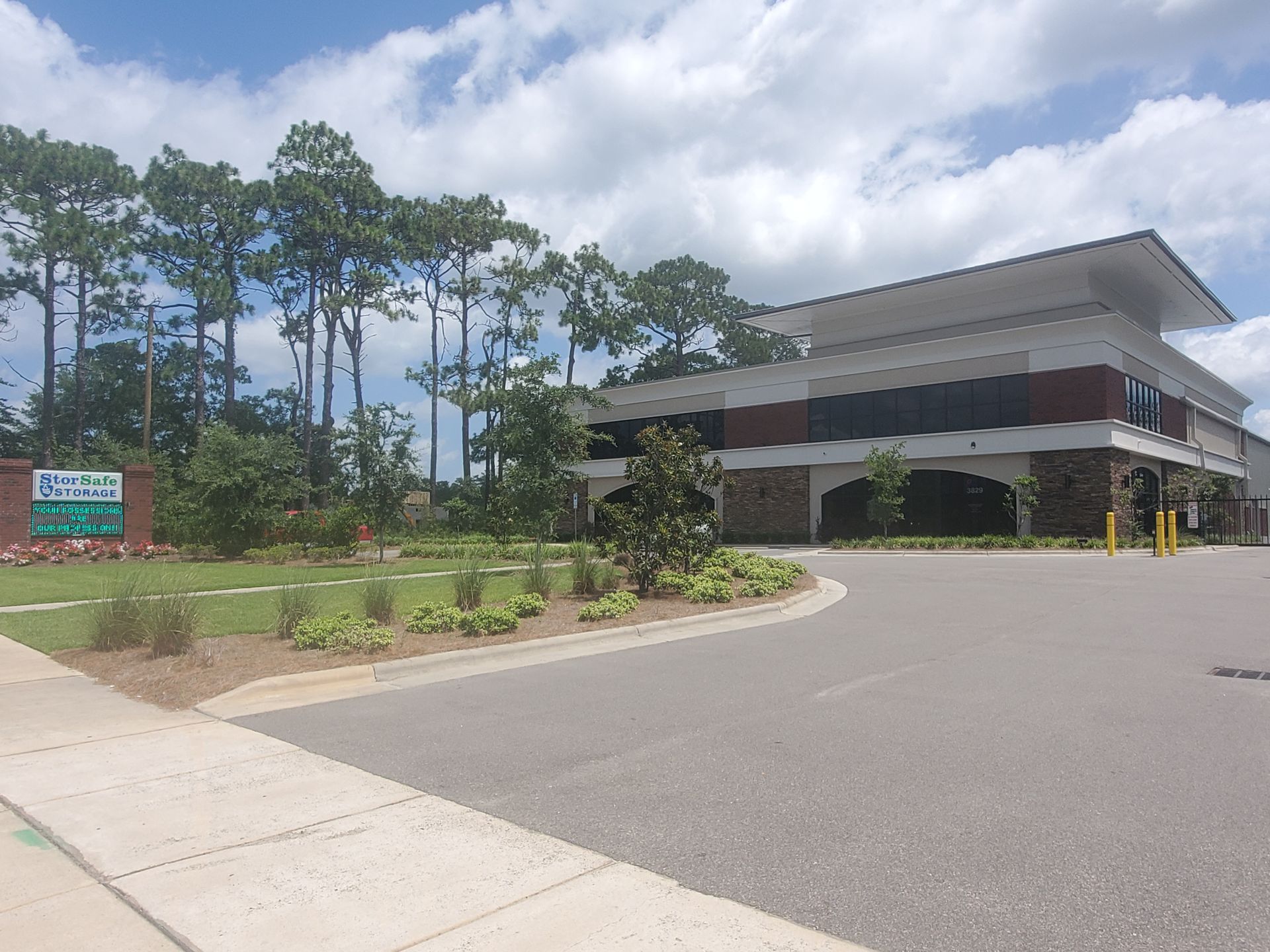 Building with a brick facade and a circular driveway on a sunny day. Trees in the background.
