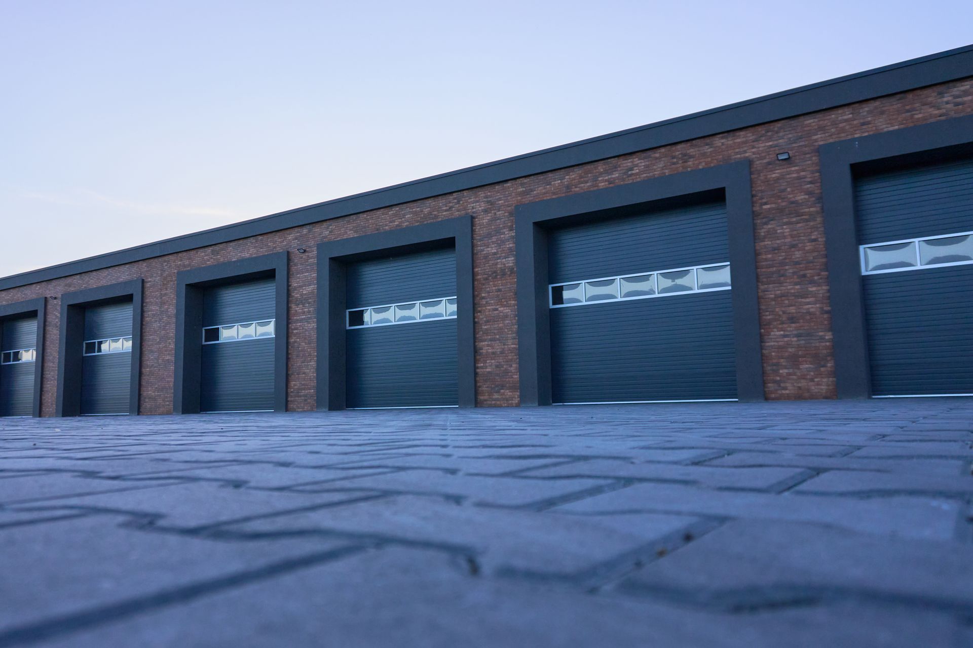 A view from below of a contemporary brick building featuring garage units.