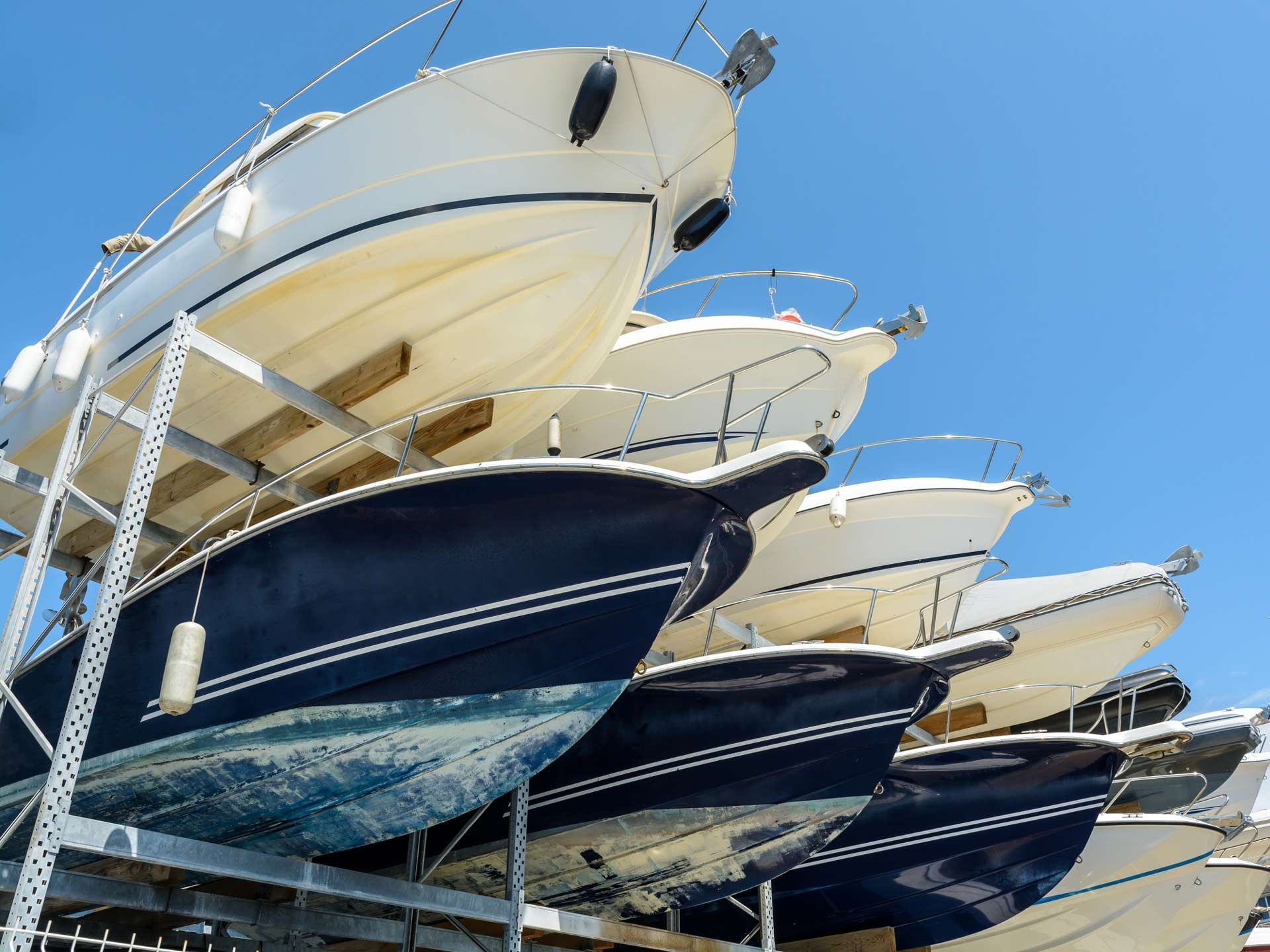 View from below of the hulls of motorboats racked one above another.
