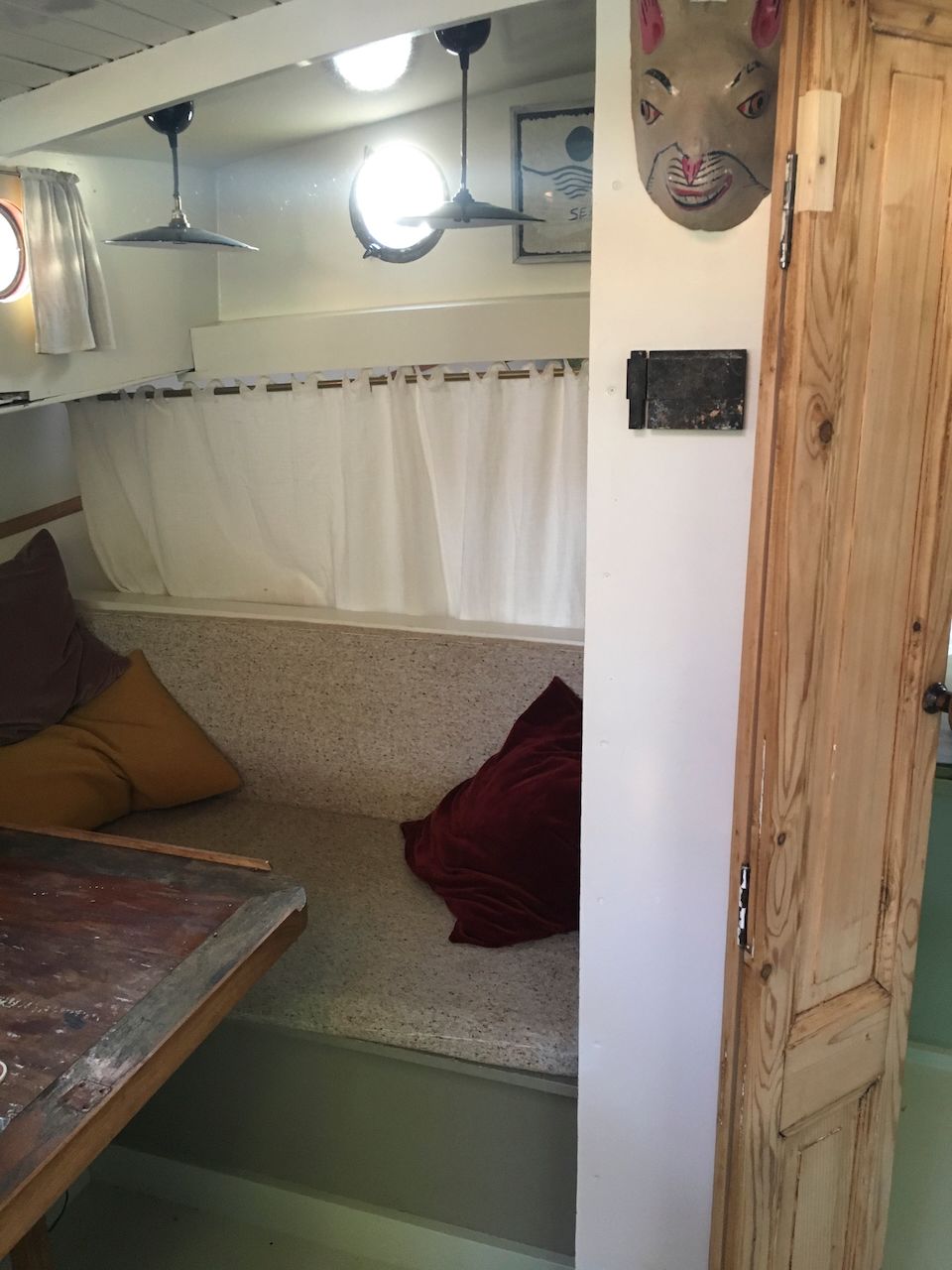 Gezellige zitjes in booth-stijl met kussens en een houten tafel in een kleine, warm verlichte binnenruimte.