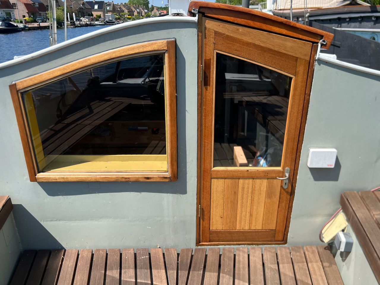 Klein dakterras met een houten deur, een groot raam en een terras met uitzicht op een stadsstraat.