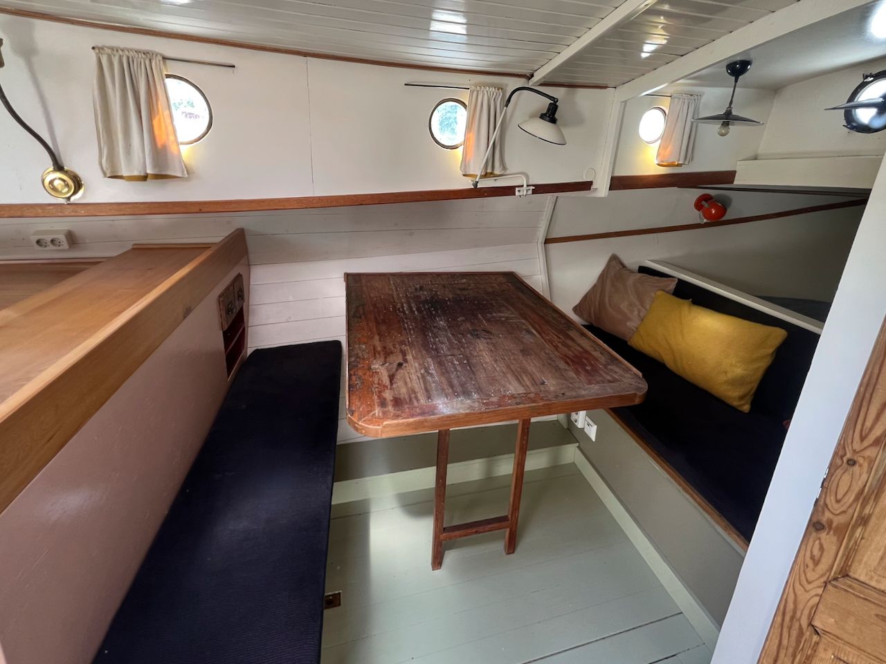 Houten tafel, zitbanken en ronde patrijspoorten.
