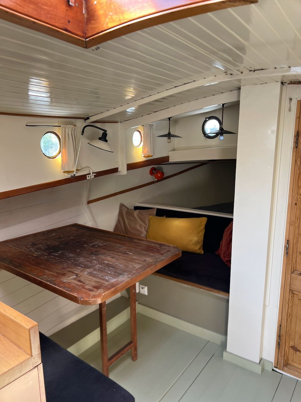 Interieur van de Wijde Blik met houten tafel, zitbanken en ronde patrijspoorten.