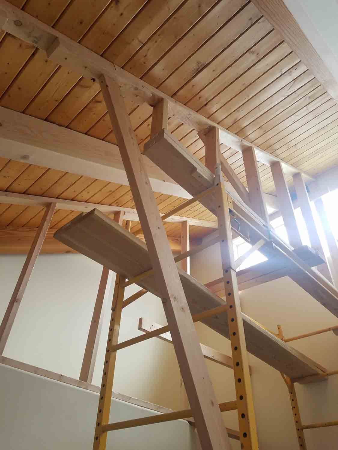 A wooden scaffolding in a room with a wooden ceiling