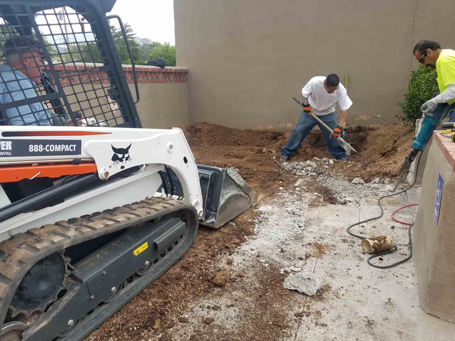 A man is digging in the dirt next to a bulldozer.