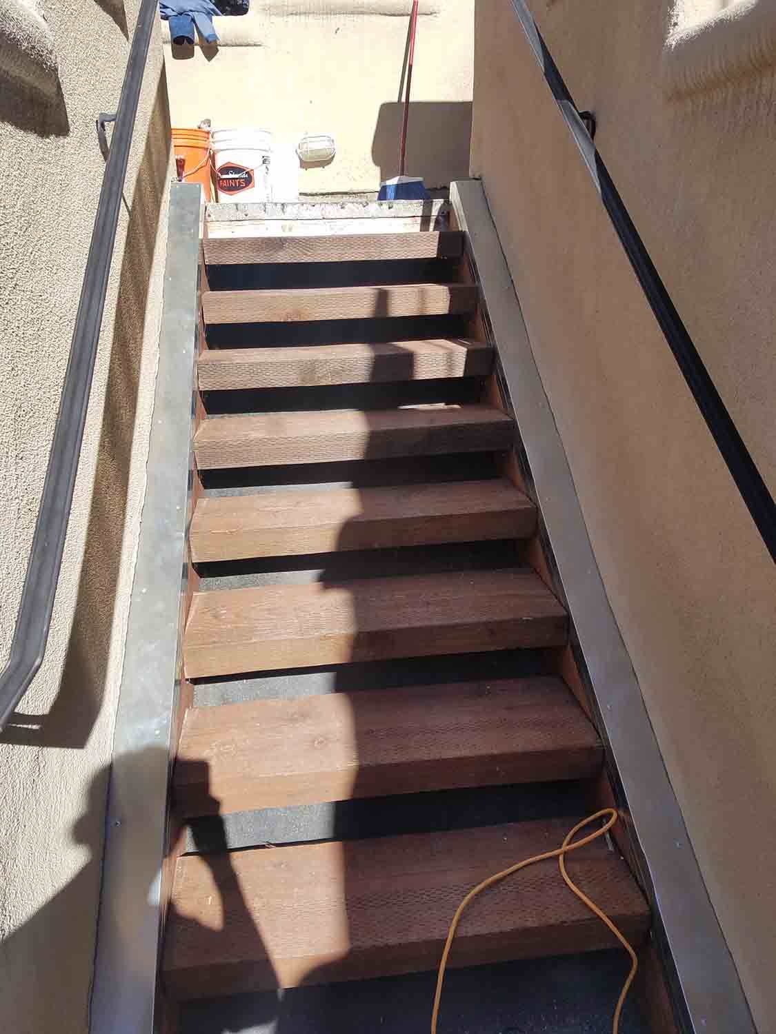 A set of wooden stairs leading up to a building with a metal railing.