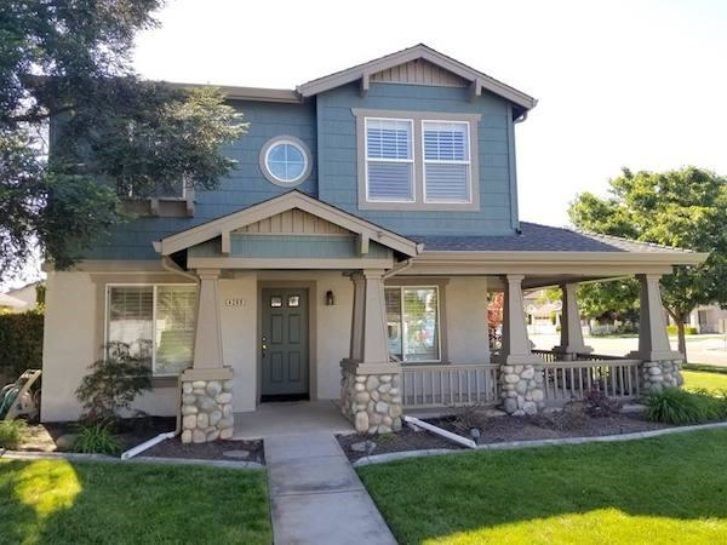 A blue house with a porch and a circular window
