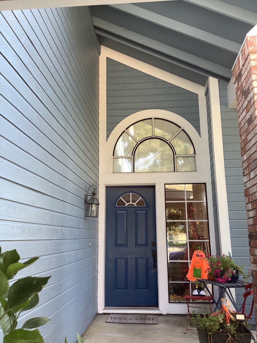 The front door of a house with a blue door and a white trim.