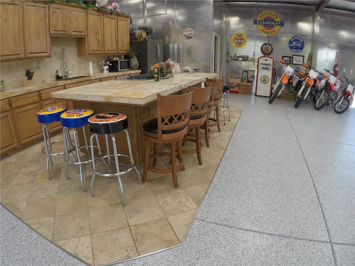A kitchen with a large island and stools and motorcycles parked in the background.