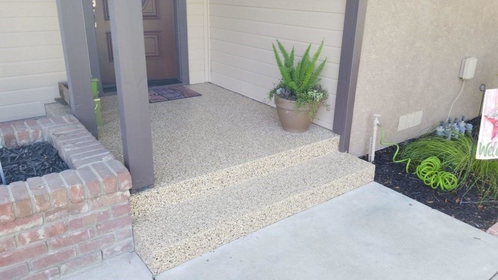 There is a potted plant on the porch of a house.