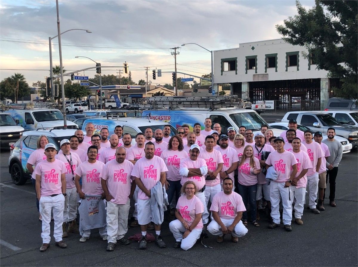 Lancaster Painting team wearing pink shirts and white pants are posing for a picture.