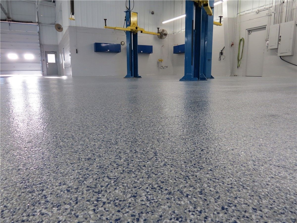 A garage with a concrete floor and two lifts.