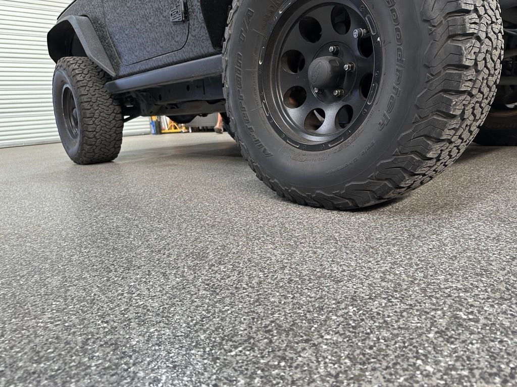 A black jeep is parked on a garage floor.