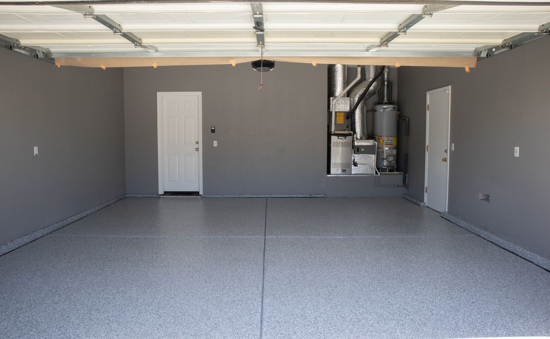 An empty garage with a gray floor and a white door.