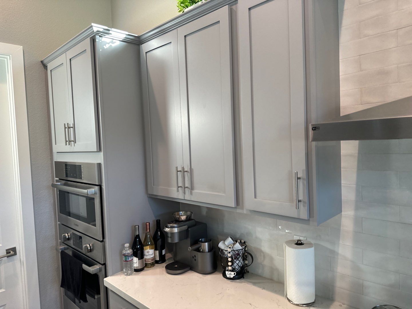A kitchen with gray cabinets and stainless steel appliances.