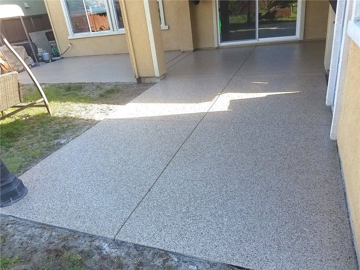 A patio with a sliding glass door in the backyard of a house.